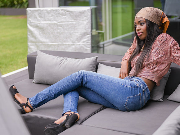 Große Frau in Jeans liegend auf einer Gartenliege