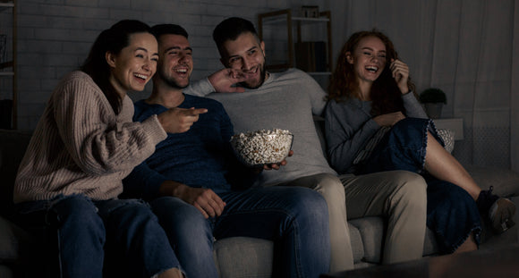 Freunde sitzen zusammen auf dem Sofa, schauen einen Film und essen Popcorn